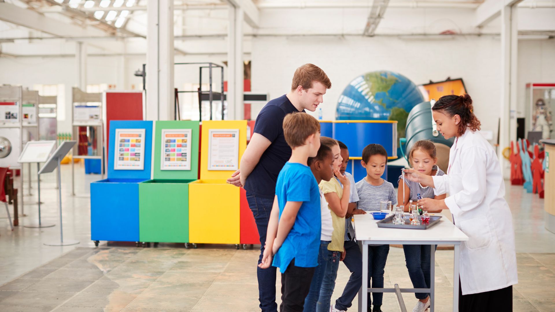 Teacher guides kids with science experiment.