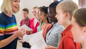 Teacher and students holding music sheets singing.