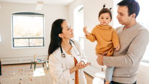 Doctor talking to parent holding child.
