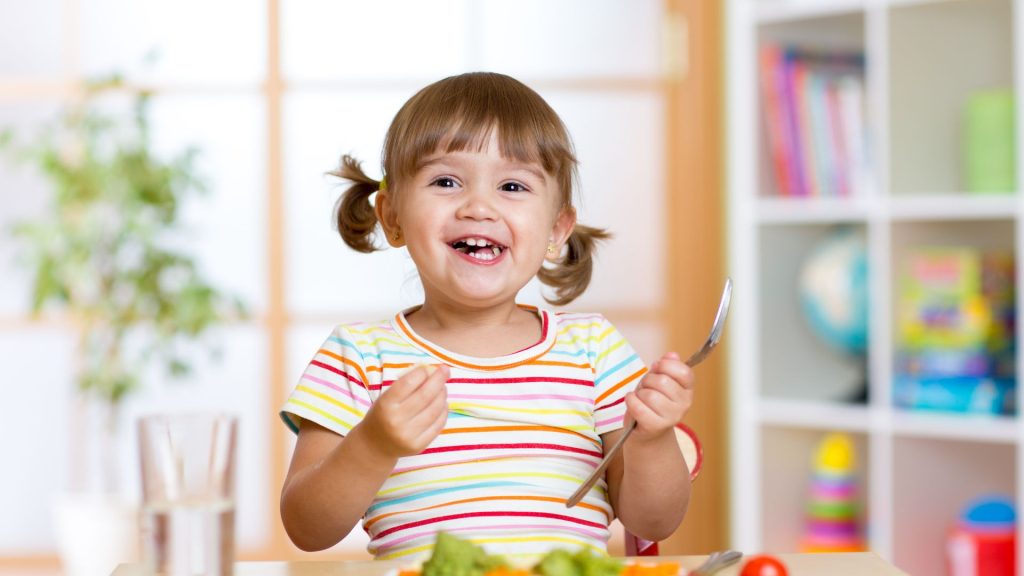 Smiling child eating vegetables
